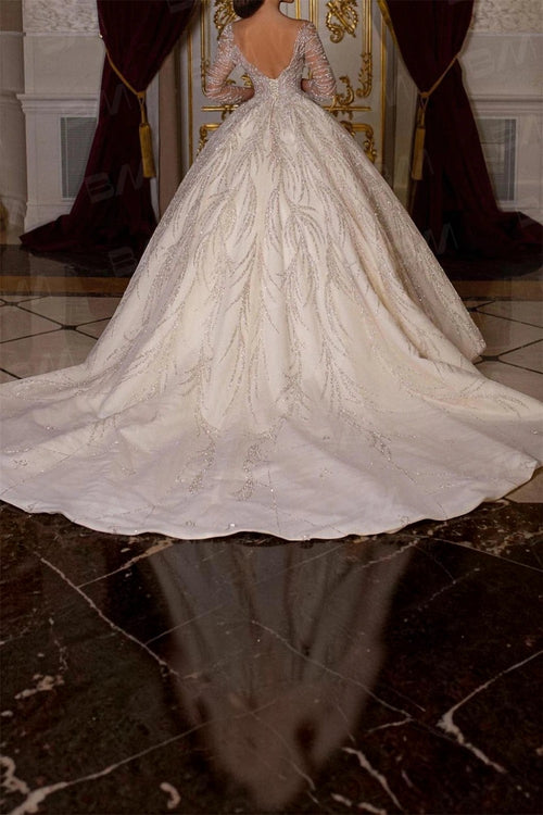 TheBlissWedding long sleeve ball gown wedding dress with intricate hand-beaded leaf patterns and a dramatic train.