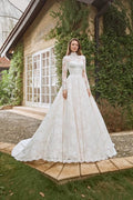 TheBlissWedding white A-line wedding dress with high neck, long lace sleeves, and intricate floral appliques outdoors.