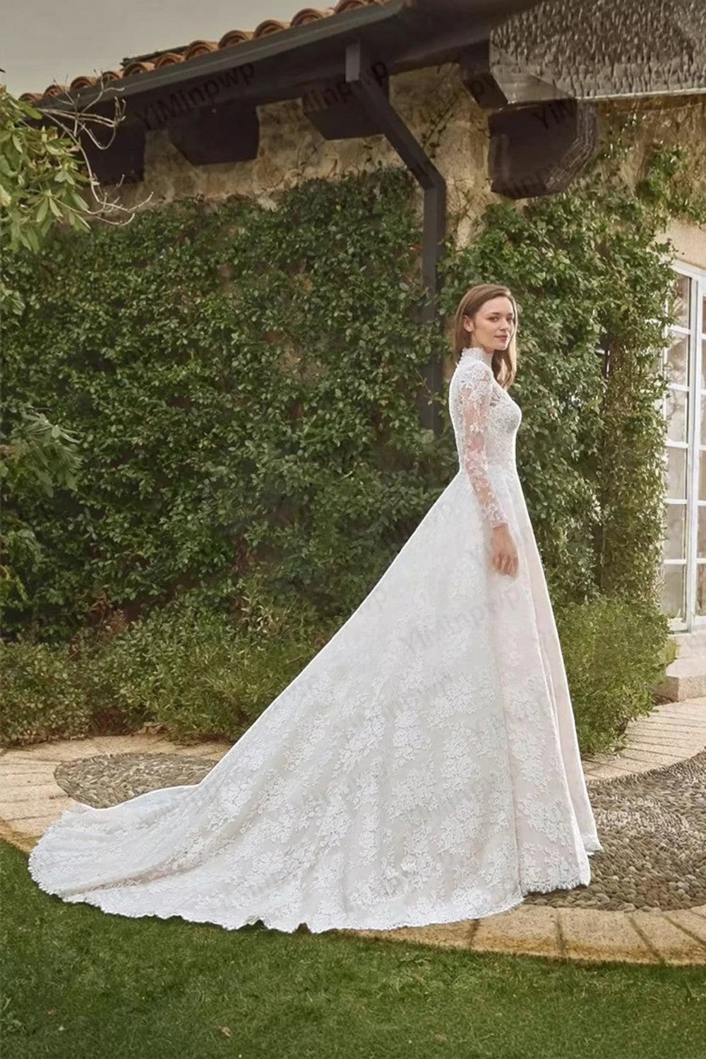 TheBlissWedding white lace A-line wedding dress with high neck, long sleeves, and sweep train in a garden setting.