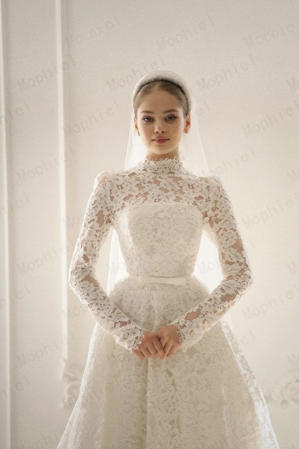 TheBlissWedding modest white A-line bridal gown with high neck, long lace sleeves, and a matching headband veil.