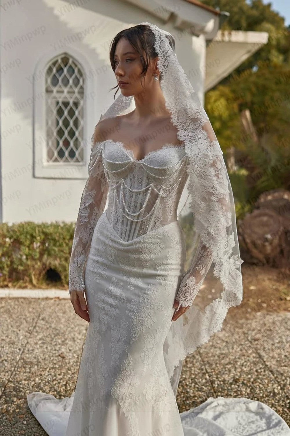 TheBlissWedding white lace mermaid wedding dress with off-shoulder long sleeves, pearl draping, and a lace veil.