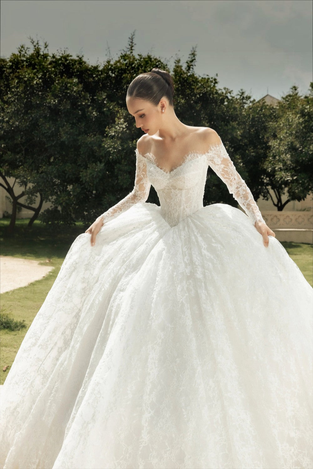 TheBlissWedding off-shoulder long-sleeve lace A-line wedding dress with a voluminous skirt in a garden setting