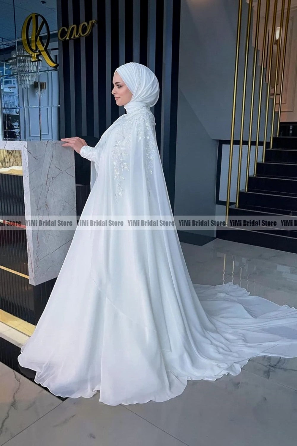 TheBlissWedding modest white chiffon wedding dress with high neck, long sleeves, and pearl detailing on a bride