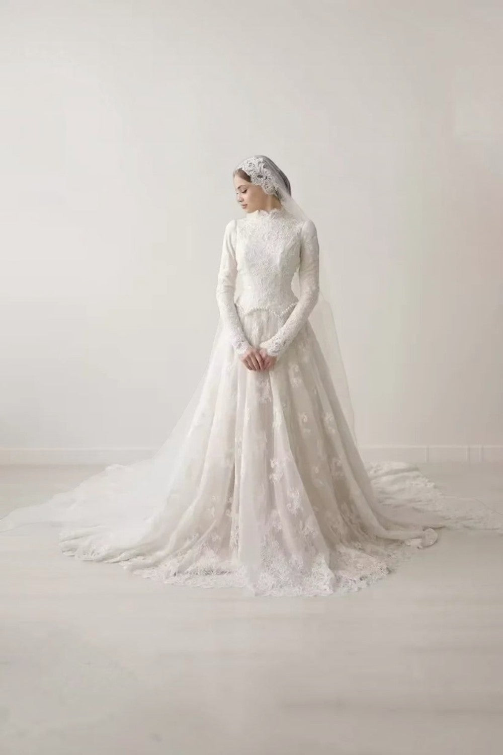 TheBlissWedding white modest wedding dress with high collar, long lace sleeves, and A-line skirt with a sweep train.