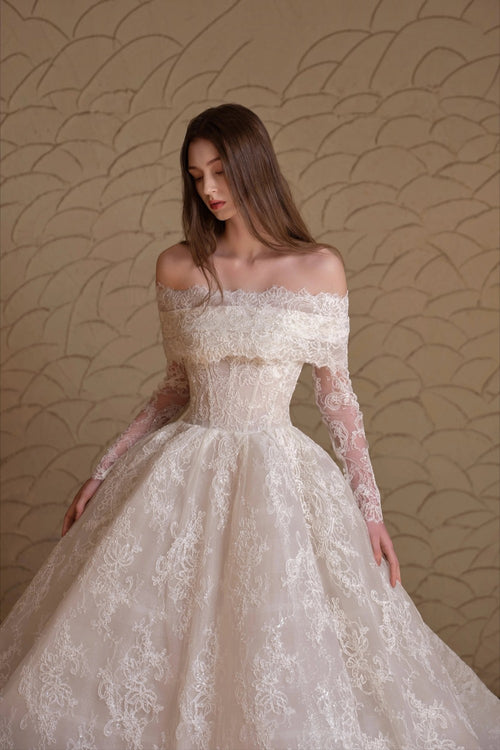 TheBlissWedding off-shoulder boho bridal gown with long lace sleeves and intricate floral appliques on an A-line skirt.