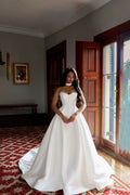 TheBlissWedding white satin A-line wedding dress with a sweetheart neckline and sleeveless bodice in a classic room.