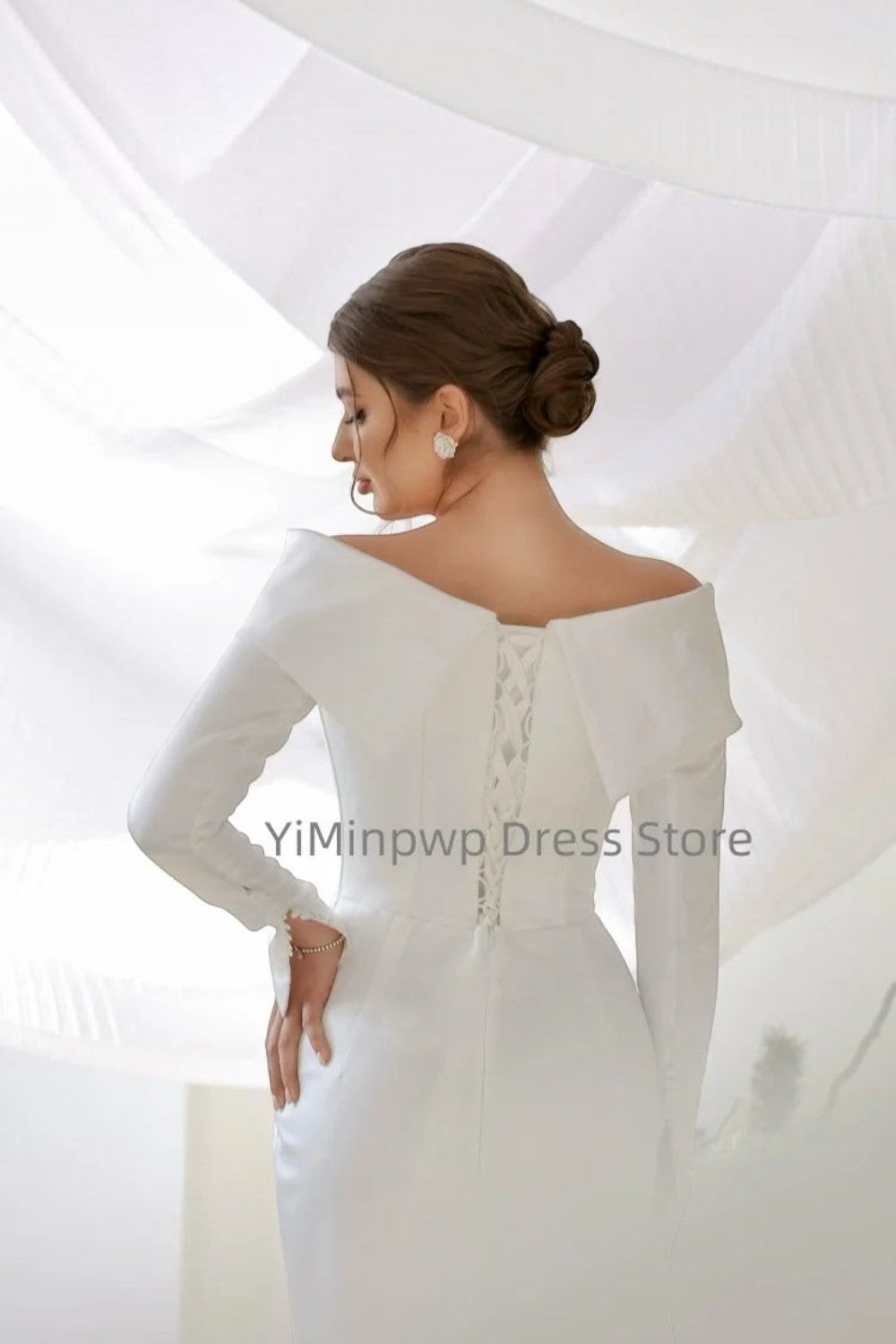 TheBlissWedding white satin mermaid wedding dress with off-shoulder neckline, long sleeves, and lace-up back detail.