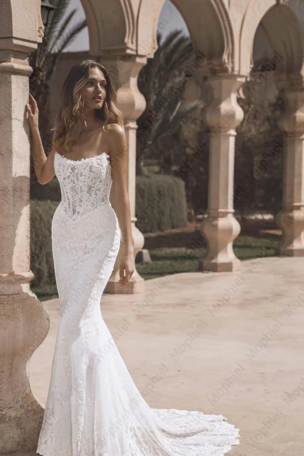 TheBlissWedding strapless mermaid wedding dress with intricate lace appliques and a fitted silhouette in an outdoor setting