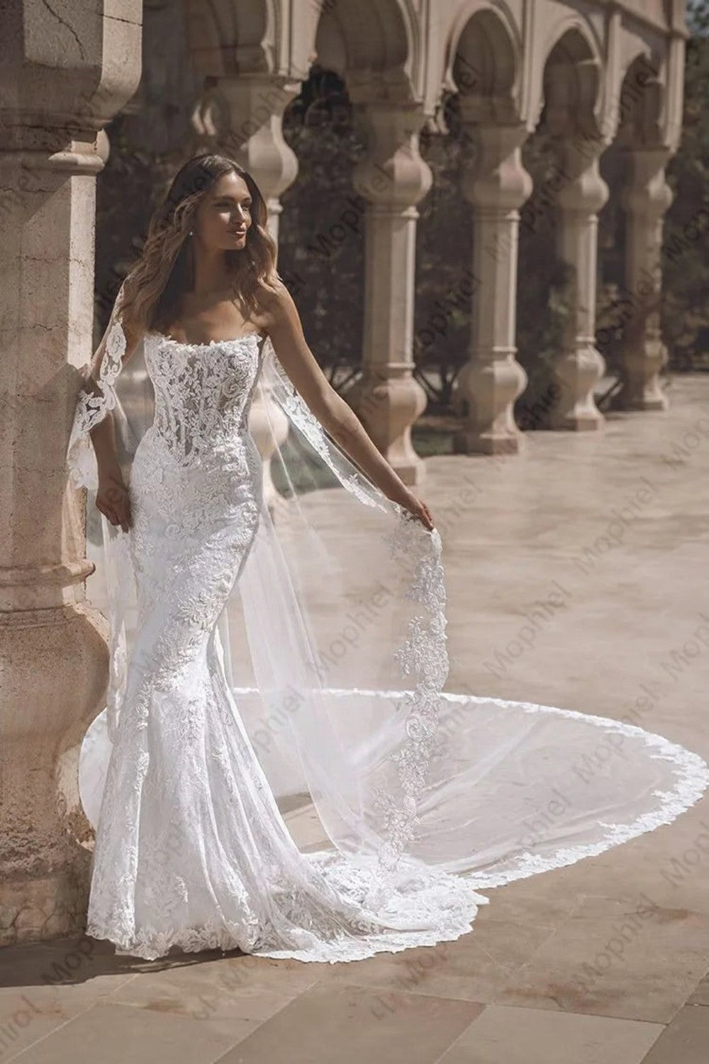 TheBlissWedding strapless mermaid bridal gown with intricate lace appliques and a dramatic detachable train.