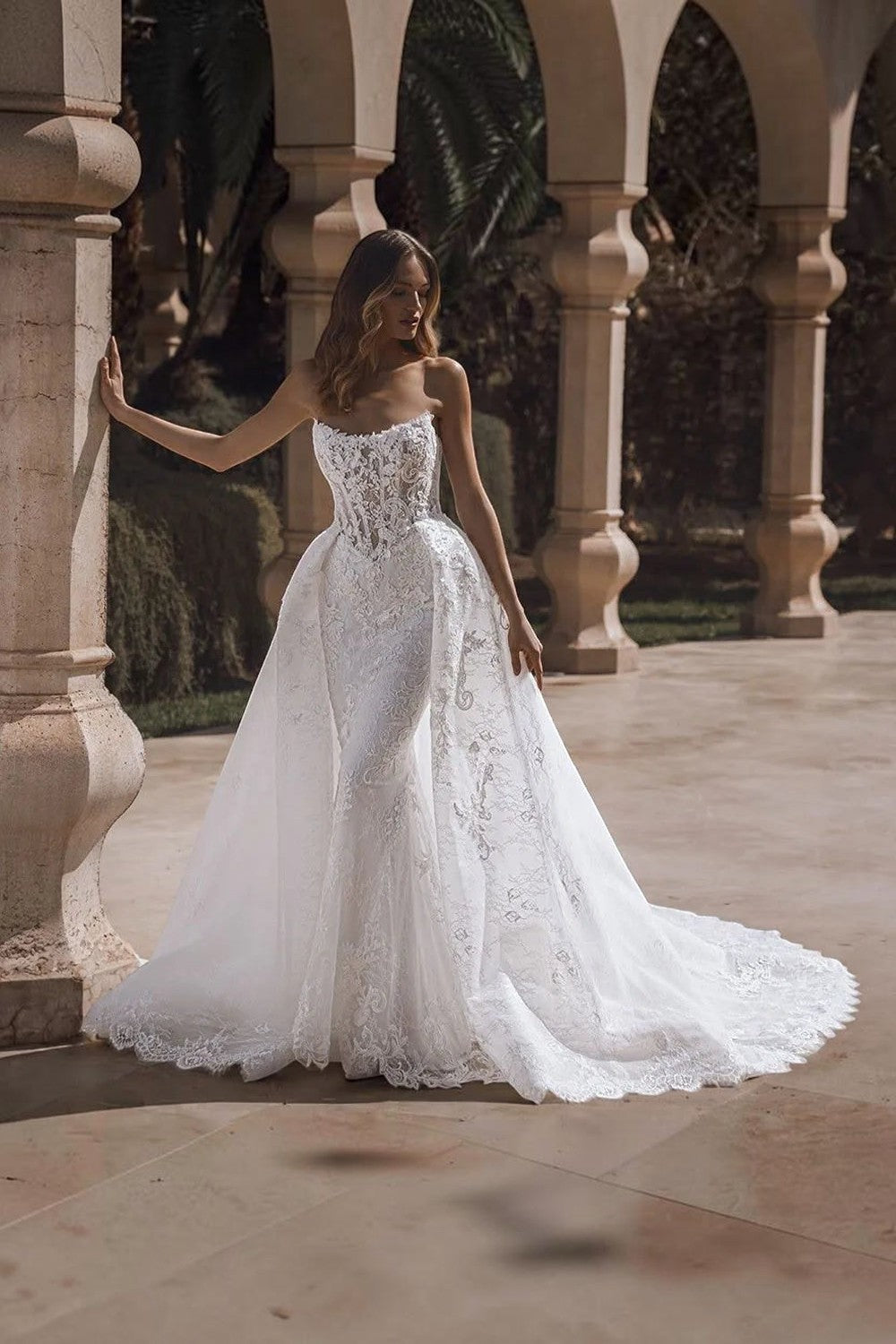 TheBlissWedding strapless mermaid bridal gown with intricate lace appliques and a dramatic detachable train.