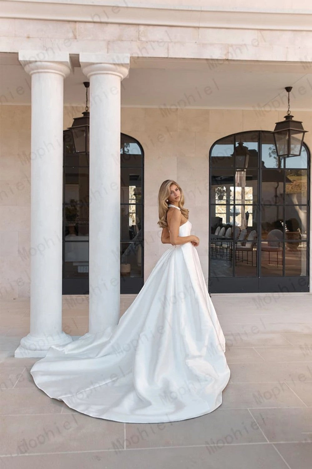 TheBlissWedding strapless white satin A-line wedding dress with a sweep train, worn by a model on a stone patio.