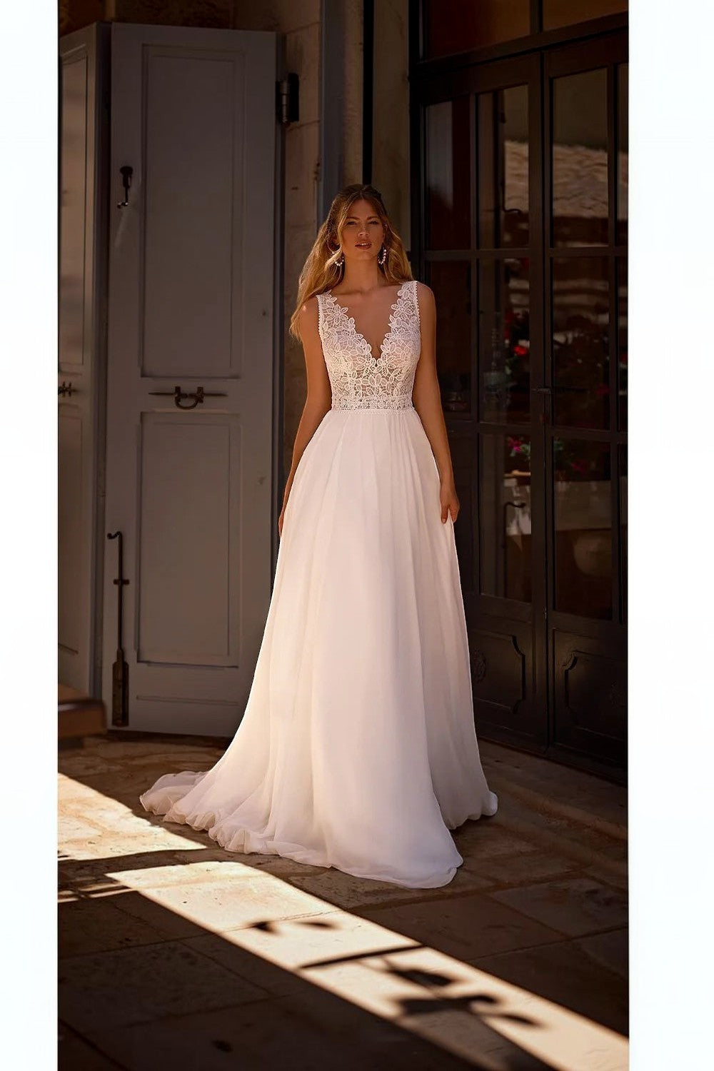 TheBlissWedding white sleeveless A-line wedding dress with a V-neck lace bodice and flowing chiffon floor-length skirt.