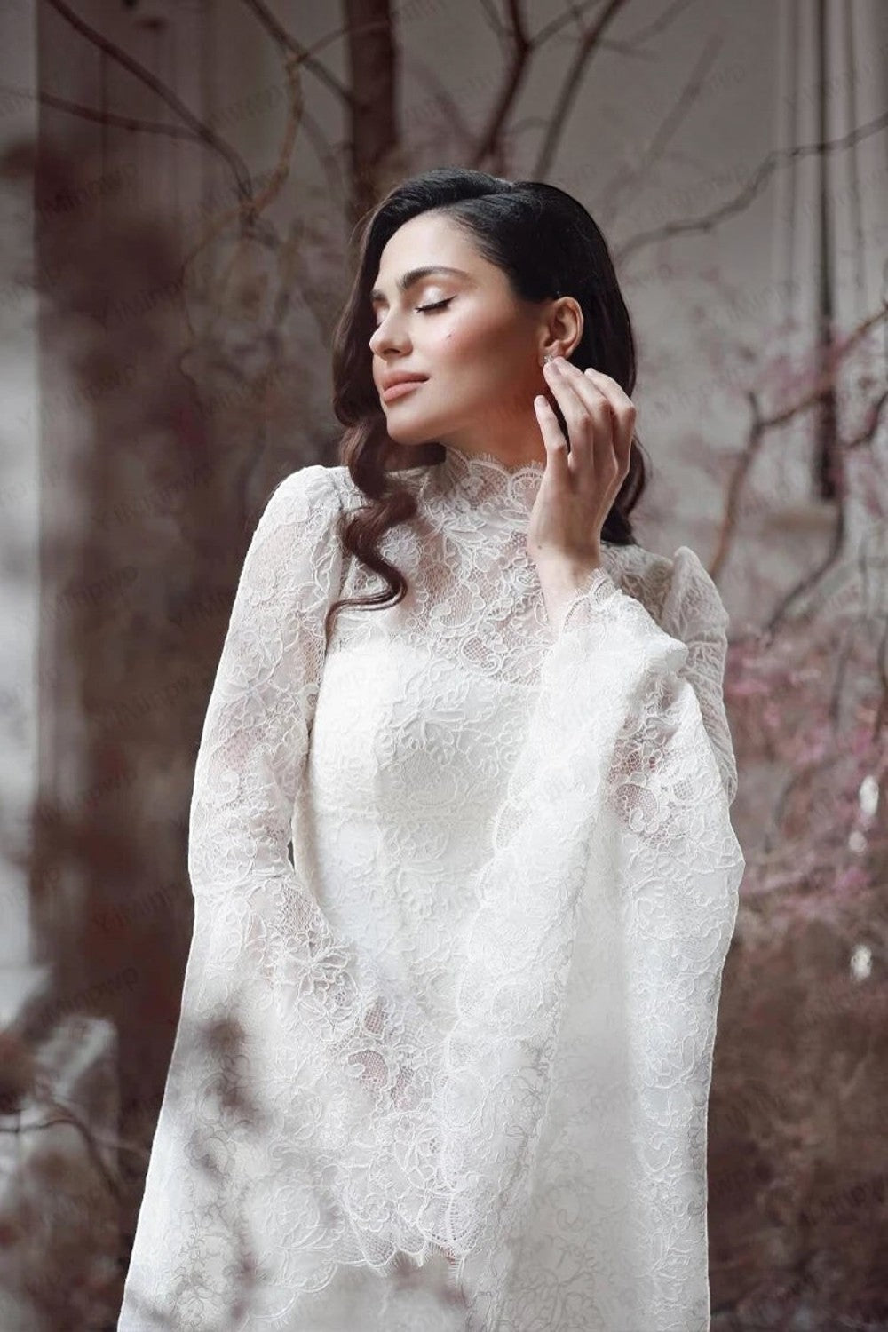 TheBlissWedding white boho wedding dress featuring a high neck, intricate lace detailing, and long flare sleeves.