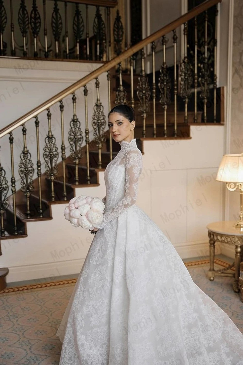 TheBlissWedding white lace A-line wedding dress with long sleeves and a sweep train worn by a bride with a bouquet.