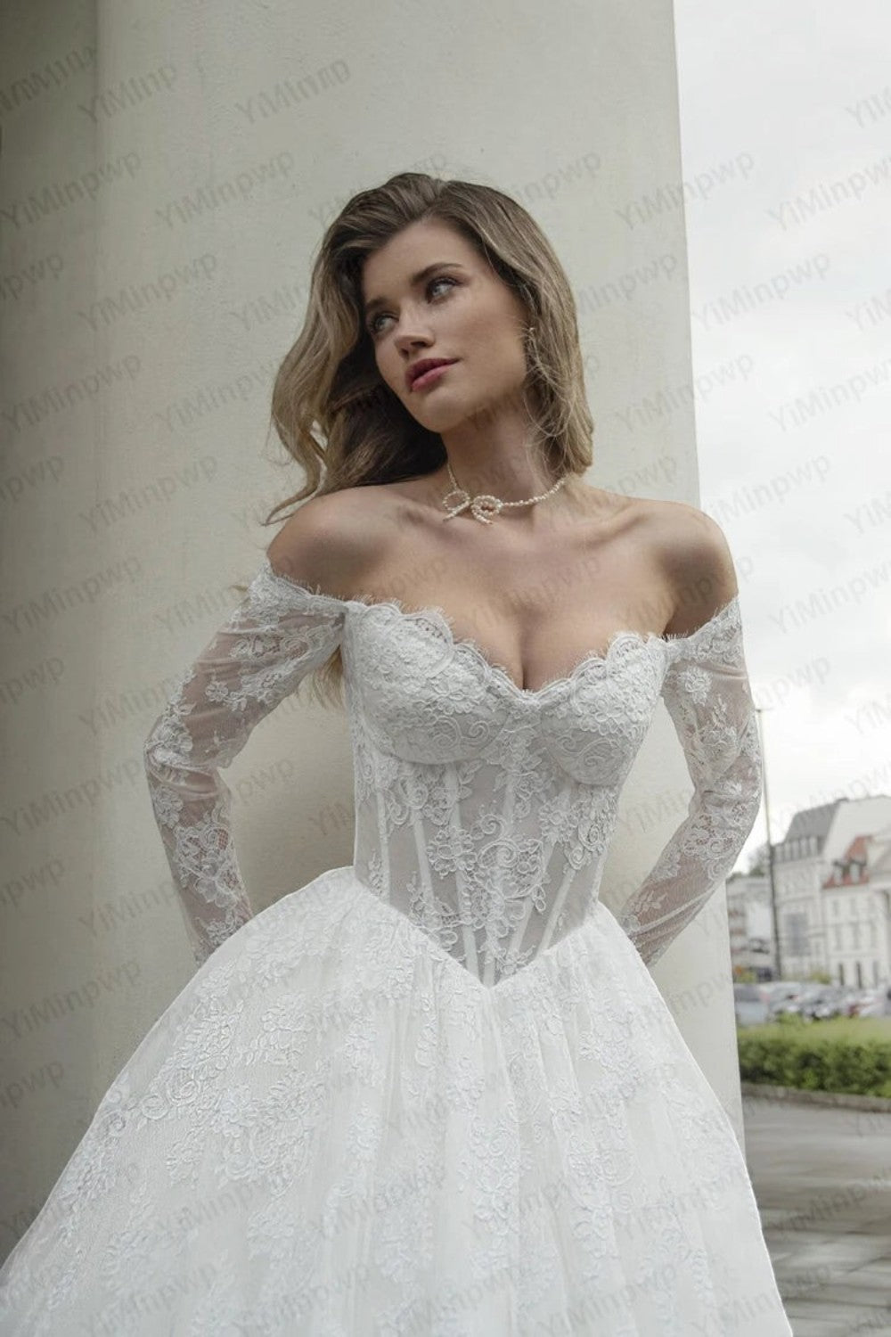 TheBlissWedding white lace wedding dress with an off-shoulder neckline, long sleeves, and a corset-style bodice.