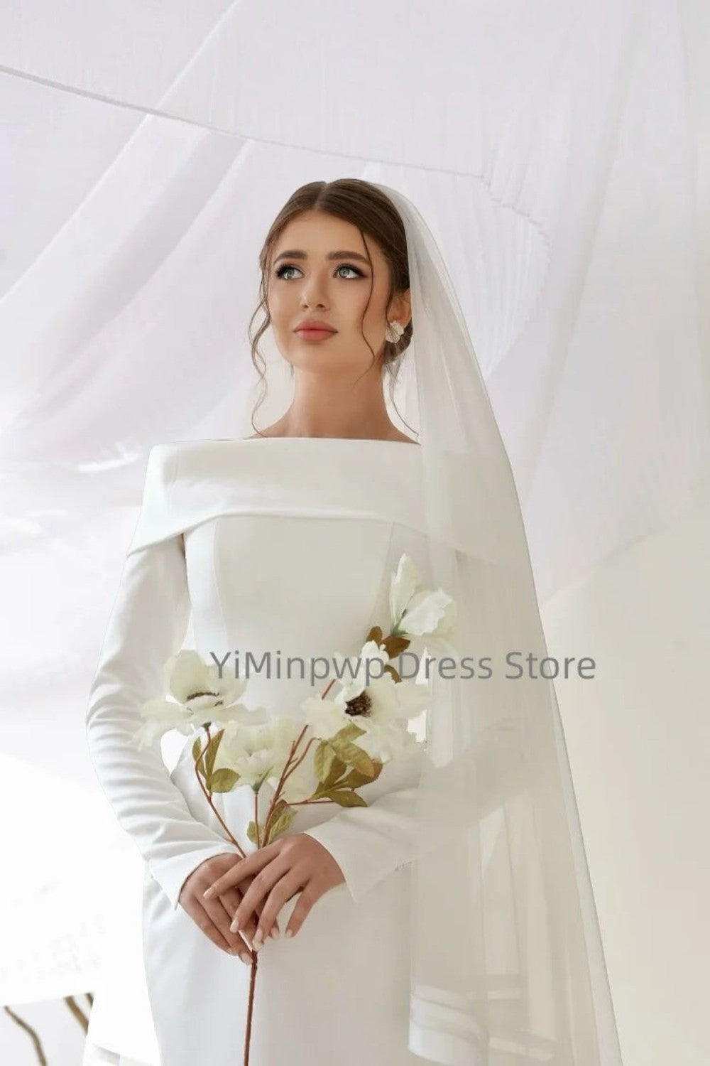 TheBlissWedding white satin mermaid wedding dress with off-shoulder neckline, long sleeves, and a delicate bridal veil.