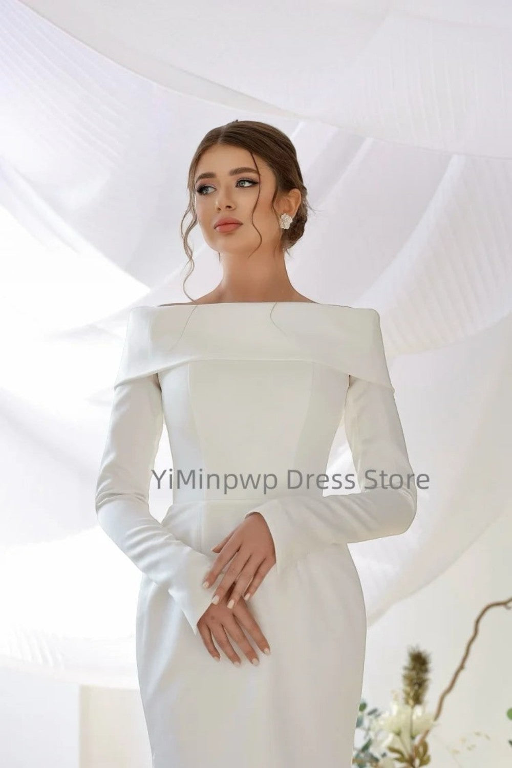 TheBlissWedding white satin mermaid wedding dress with off-shoulder neckline and long sleeves on a model.